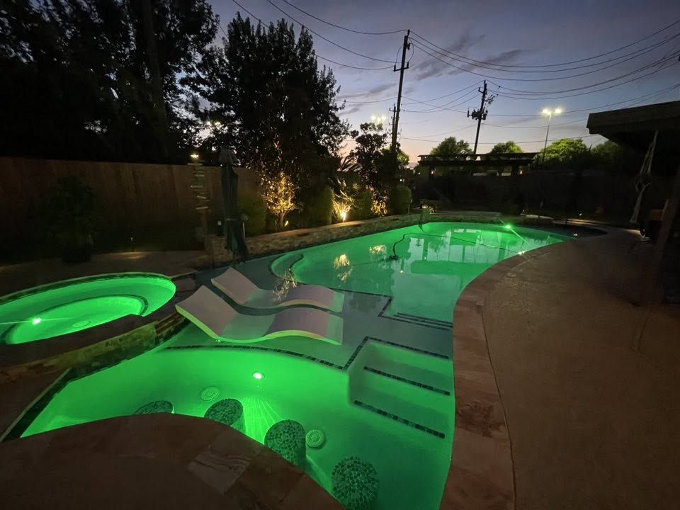Residential swimming pool illuminated with green underwater lighting at night